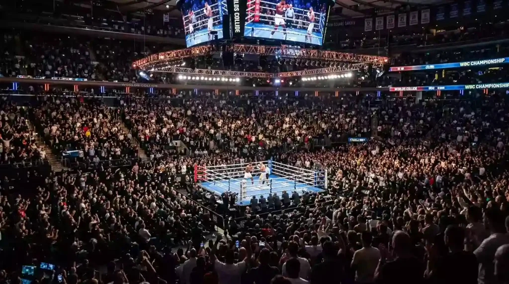 Salle de boxe comble avec des milliers de spectateurs assistant à un méga-combat professionnel